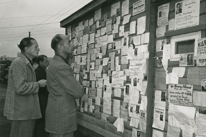 People in front of notices with information about missing persons